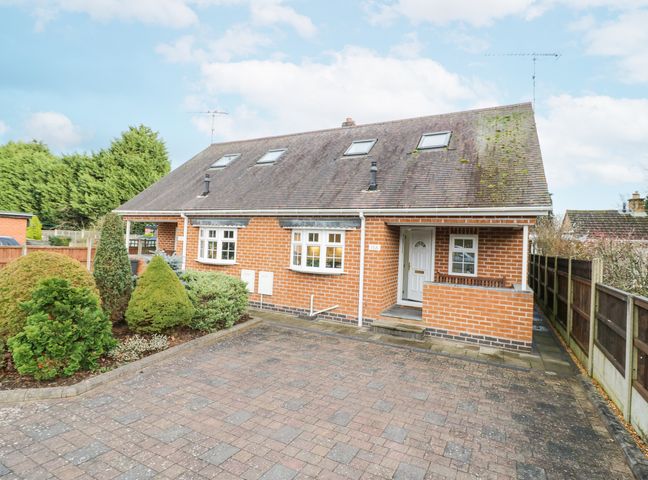 A brick house with four skylights a white front door shrubs and a paved driveway at Hen and Chickens in Stourport-On-Severn