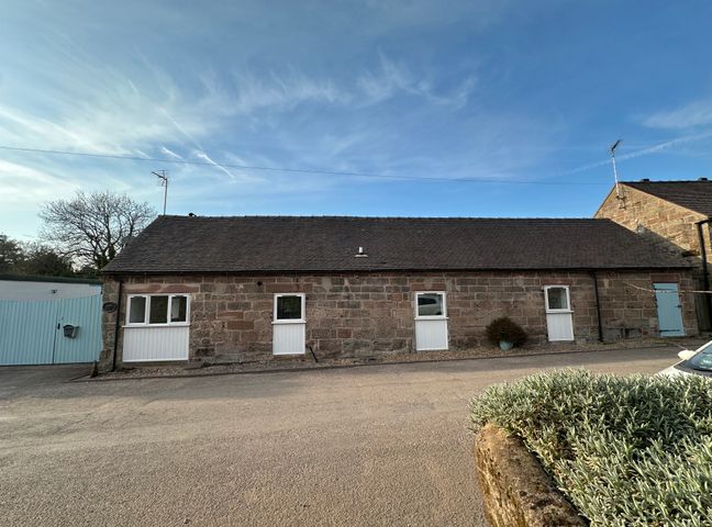 A stone building with white doors and windows and a blue gate under a clear sky at The Old Parlour in Alton