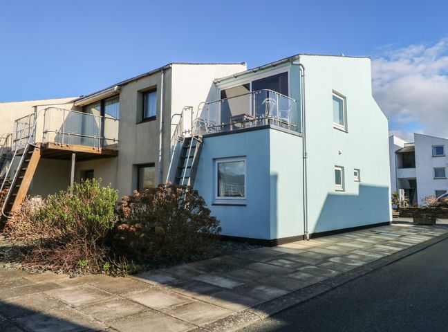 A two story building with external staircases and balconies with glass railings at The Moorings Apartment in Porthmadog