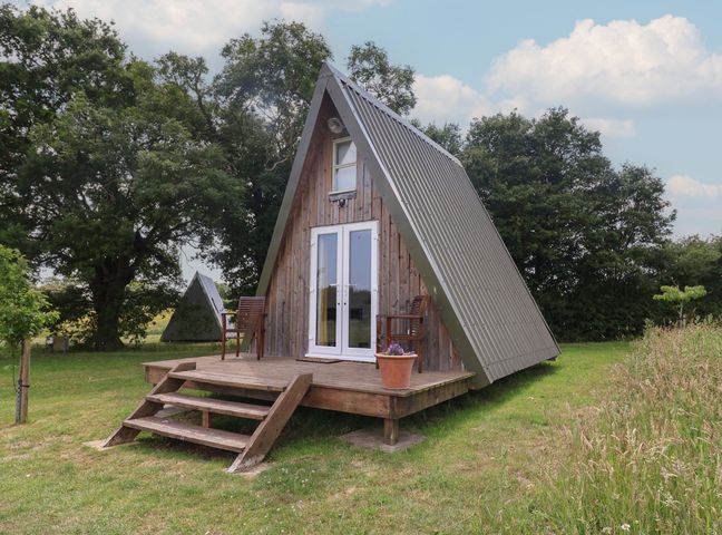An A-frame house with a wooden deck and chairs at A-frame in Monewden near Otley, Suffolk