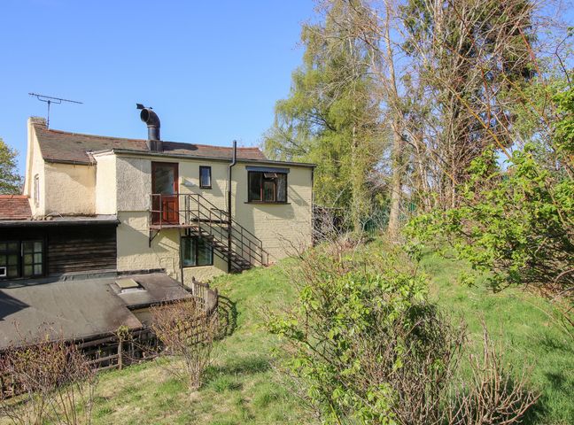 A house with an external staircase and a grassy garden with bushes and trees at The Miller's Roost at Dudgeley Mill in All Stretton near Church Stretton