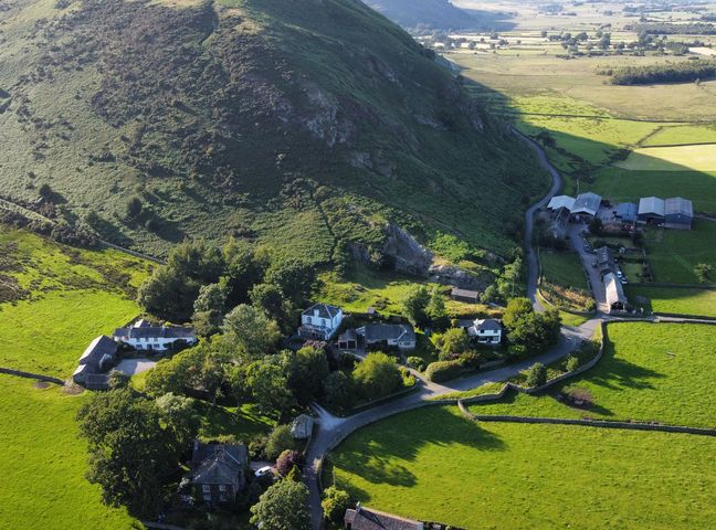 An aerial view of houses and fields near a mountain at The School at Mungrisdale in Mungrisdale near Keswick