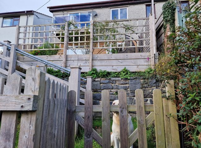 An outdoor area with a wooden fence and steps leading to a house at Golygfa Abergele