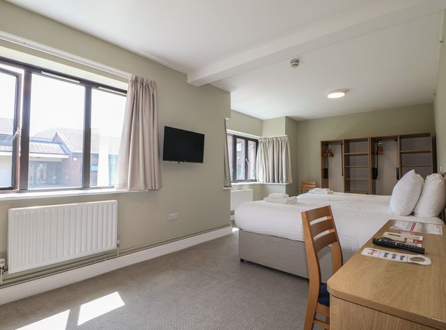 A bedroom with a bed, desk, chair, and television at Bedroom 6 in Littlehampton