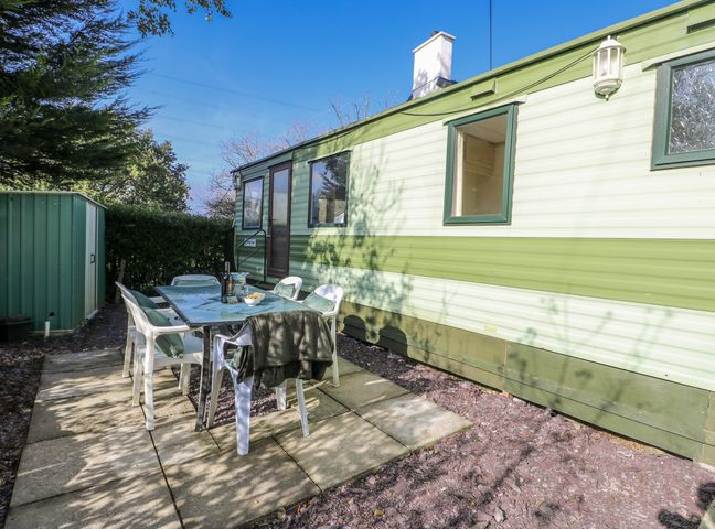 An outdoor patio area with a table and chairs at Meadow Island Caravan in Penygroes