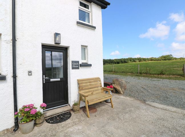 An entrance with a bench and flowers at Coach House Cottage 