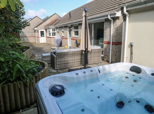 An outdoor area with a hot tub and seating at Jaluna in Carbis Bay