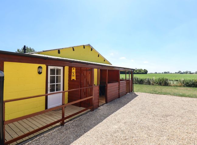 A yellow building with wooden features and a gravel area at Lancaster in Lincoln