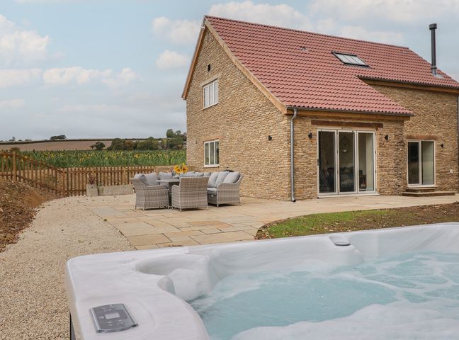An outdoor area with a hot tub and seating at Foxes Den in Pendomer near Yeovil, Somerset