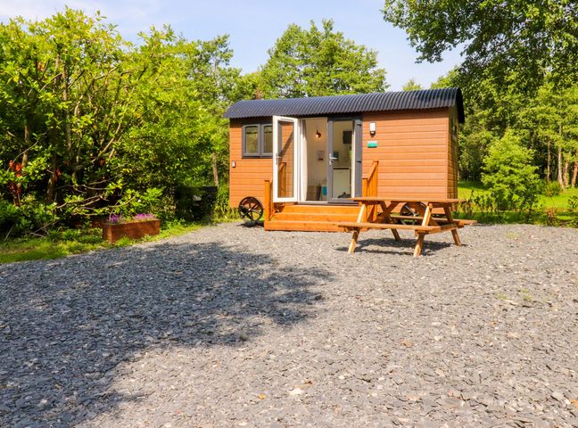 A shepherd's hut with outdoor seating at Shepherds Hut 2