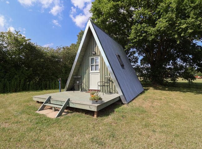An A-frame cabin with a small deck and chairs at 1 Bed Sleeps 2, Shared Bathroom in Monewden near Otley, Suffolk
