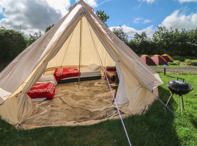 A tent with beds and a grill outside at Bell Tent One