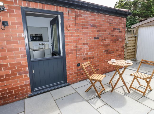 An outdoor area with a door, table and chairs at Little Birchinlea in Glossop
