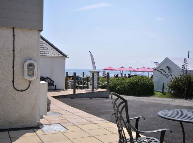 An outdoor area with a charging point and seating overlooking the sea at Evelyn in Looe