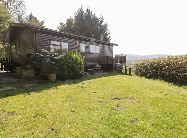An outdoor area with a cabin and grassy space at Springtime Lodge Rhyd-y-Foel near Abergele