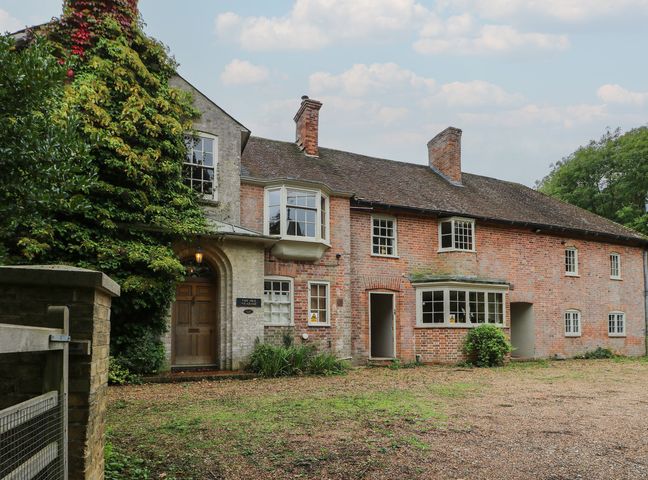 A brick house with windows and a door in a garden at The Old Vicarage