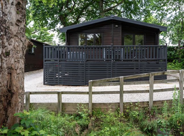 A black wooden house with a deck and fence at Watendlath in Keswick