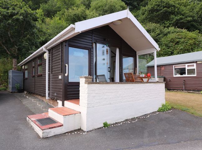 A cabin with porch seating and steps at Captain's Cabin, Clarach Bay near Aberystwyth