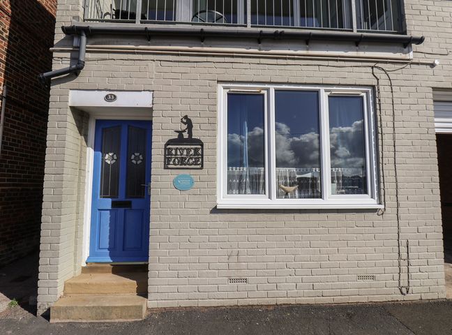 An exterior view with a blue door, window, and sign at Farriers Yard in Whitby