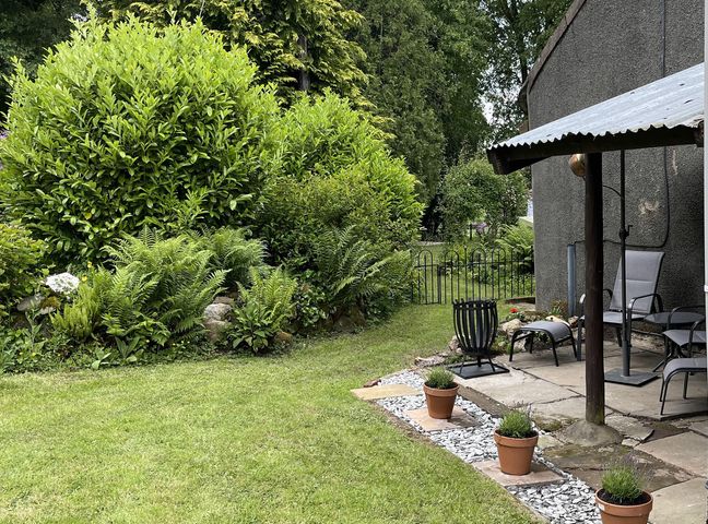 A garden with bushes and patio chairs at High Dyke Cottage