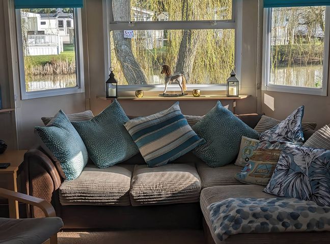 A living room with a couch and pillows near windows at the property located by the water