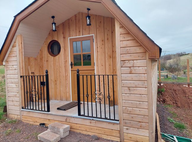 A wooden cabin with a door and railing features at an outdoor location