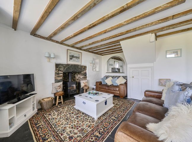 A living room with a fireplace and sofa at Bwthyn Nain in Harlech