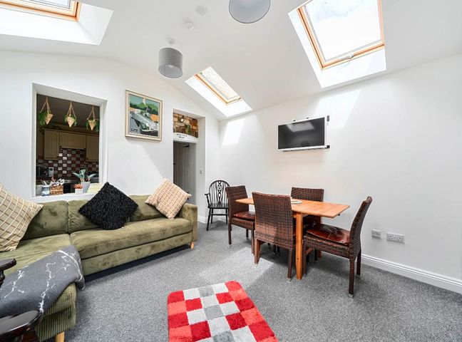 A living room with a sofa and dining area at Charming Lincoln Cottage in Lincoln