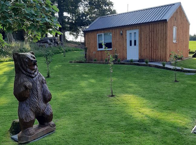 A garden with a wooden cabin and a bear statue at Taigh Nam Moireach in Inverness