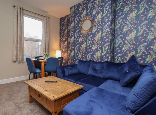 A living room with a blue sofa and wooden coffee table at Apartment 2, Blackburn Heights in Bridlington