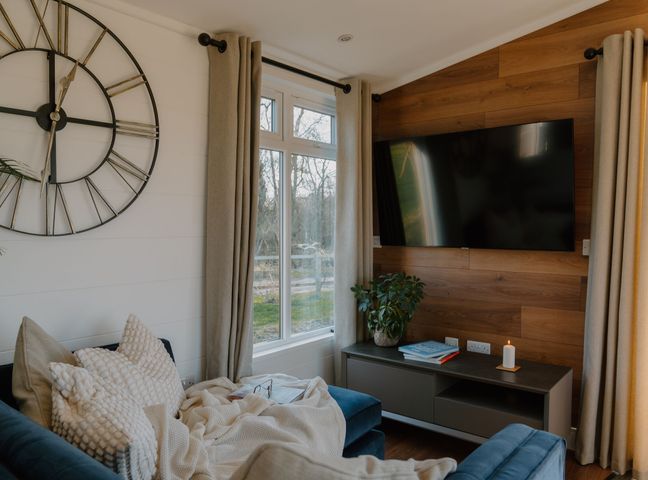 A living room with a clock and television at The Elton in Kings Cliffe
