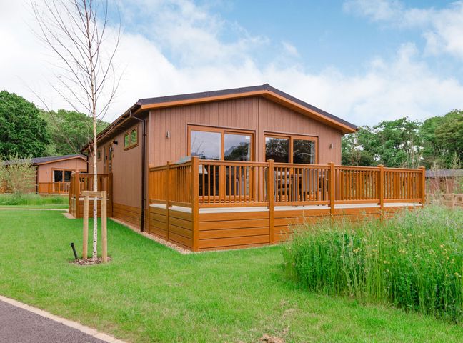 A lodge with decking and windows at The Kingscliffe (Pet) in Kings Cliffe