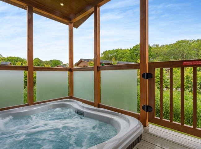 A hot tub on a deck with wooden railing at The Sutton (Pet) Kings Cliffe