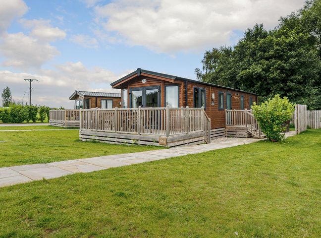 A lodge with a deck and surroundings at Alder Waterside Spa Carlton Miniott near Thirsk