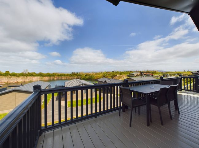 A balcony with a table and chairs overlooking a lake at Keswick in Penrith