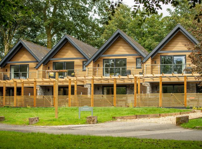 A row of wooden houses with balconies and large windows at Kilden Pet in Praze-An-Beeble