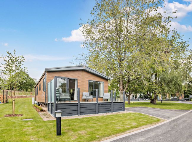 A mobile home with a deck and trees in an outdoor area at Saron 2.0 Pet in Llandyrnog