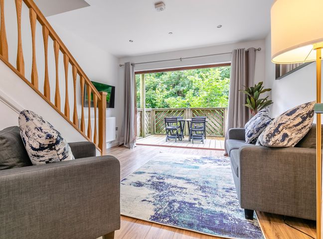 A living room with a sofa and television at Treehouse Spa in Perranporth