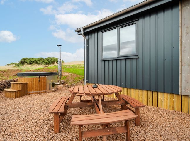 An outdoor area with a hot tub and a wooden table with benches at The Townsend in North Berwick
