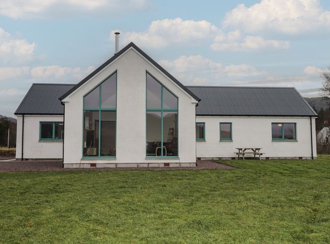 A house with large windows and a picnic table at Sonas in Strathcarron