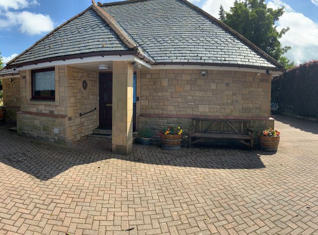 A house with a brick pathway and flower pots at Fenton Drive Wooler