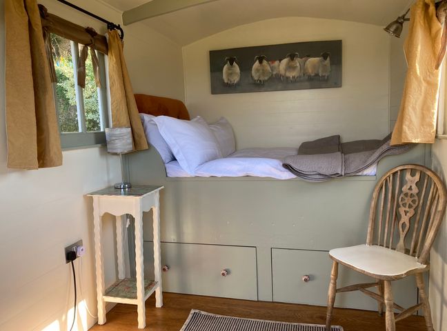 A bedroom with a bed and chair at Cosy Shepherd’s Hut Longhope