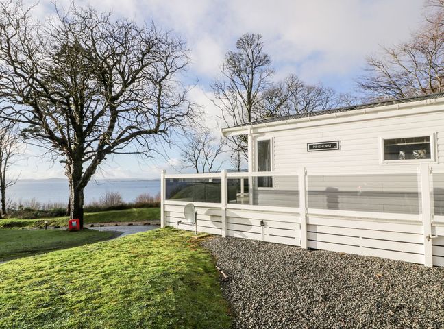 A house with a gravel area and a tree near a lake at Serenity Lodge Wemyss Bay