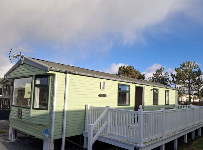A mobile home with a deck and trees at Caravan in 