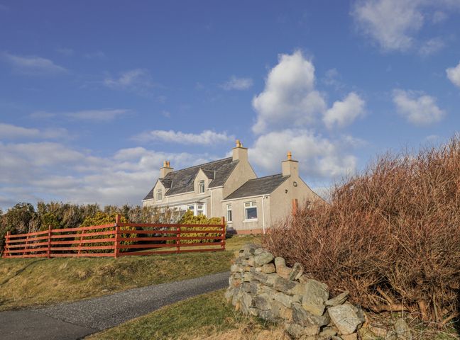 A house with a red fence and a pathway at 15 New Shawbost in Shawbost