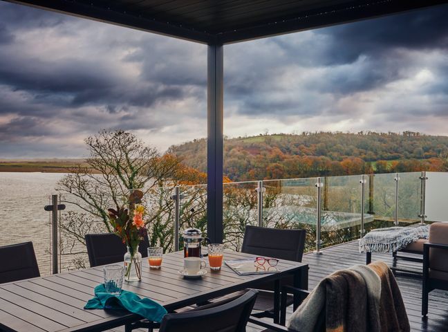 An outdoor area with a table and chairs overlooking a river at Wilde Spa (Pet) Carmarthen
