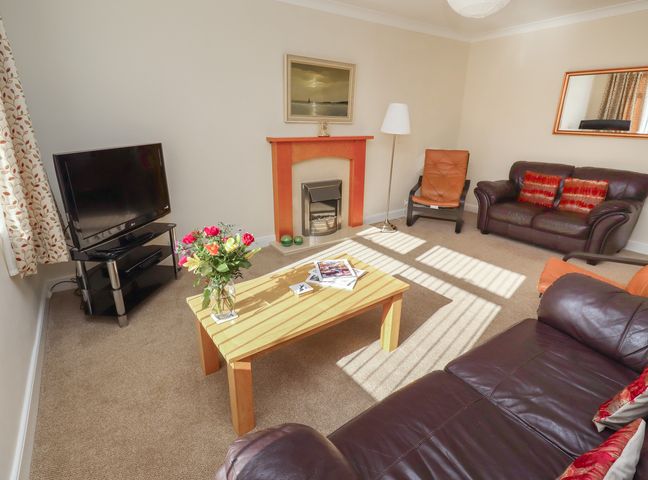 A living room with a television and coffee table at Kittiwake at No 20 Seahouses