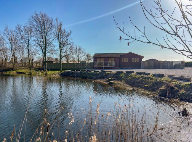 A water body with a building and trees at Star Carr Lakes