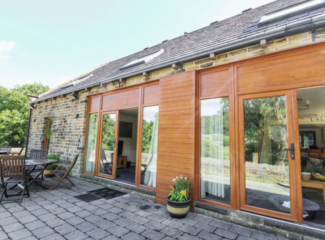 An outdoor patio with wooden furniture at Cragg Hall View in Cragg Vale
