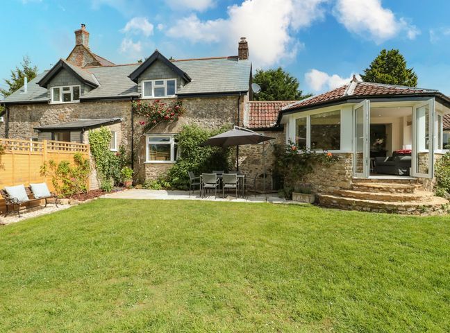 A garden with a table and chairs in front of a house at Ammerham Farm Cottage Ammerham near Winsham